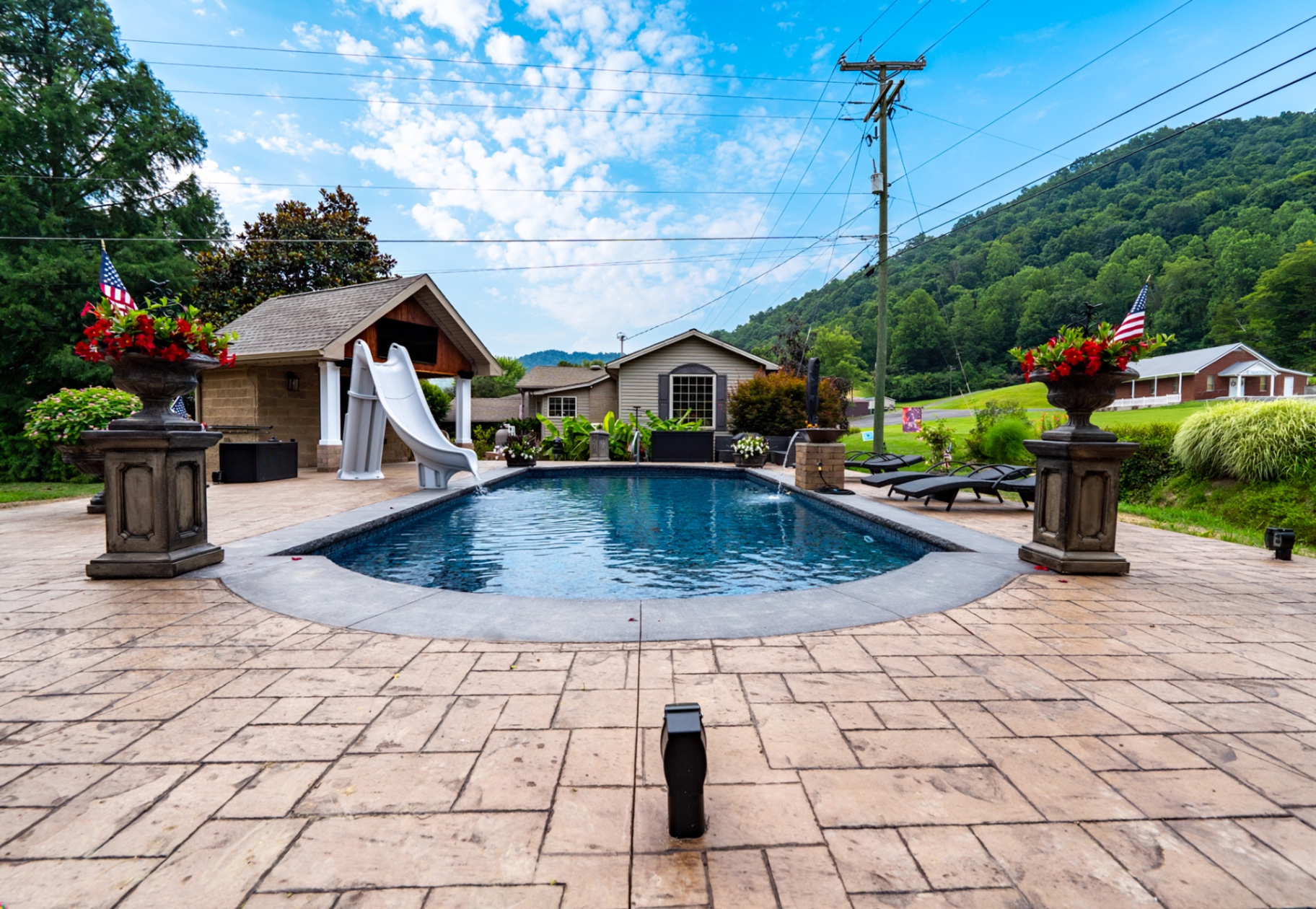 Freeform pool with stone pillars and paver deck