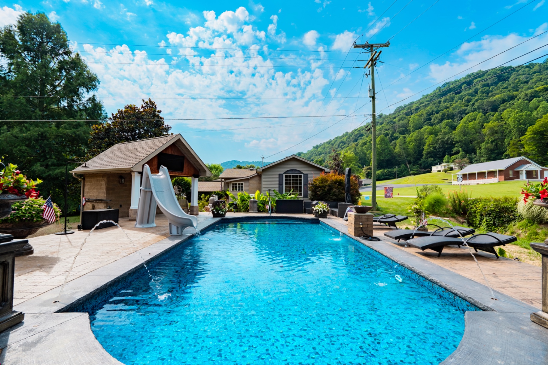 Custom in-ground pool with slide and mountain backdrop